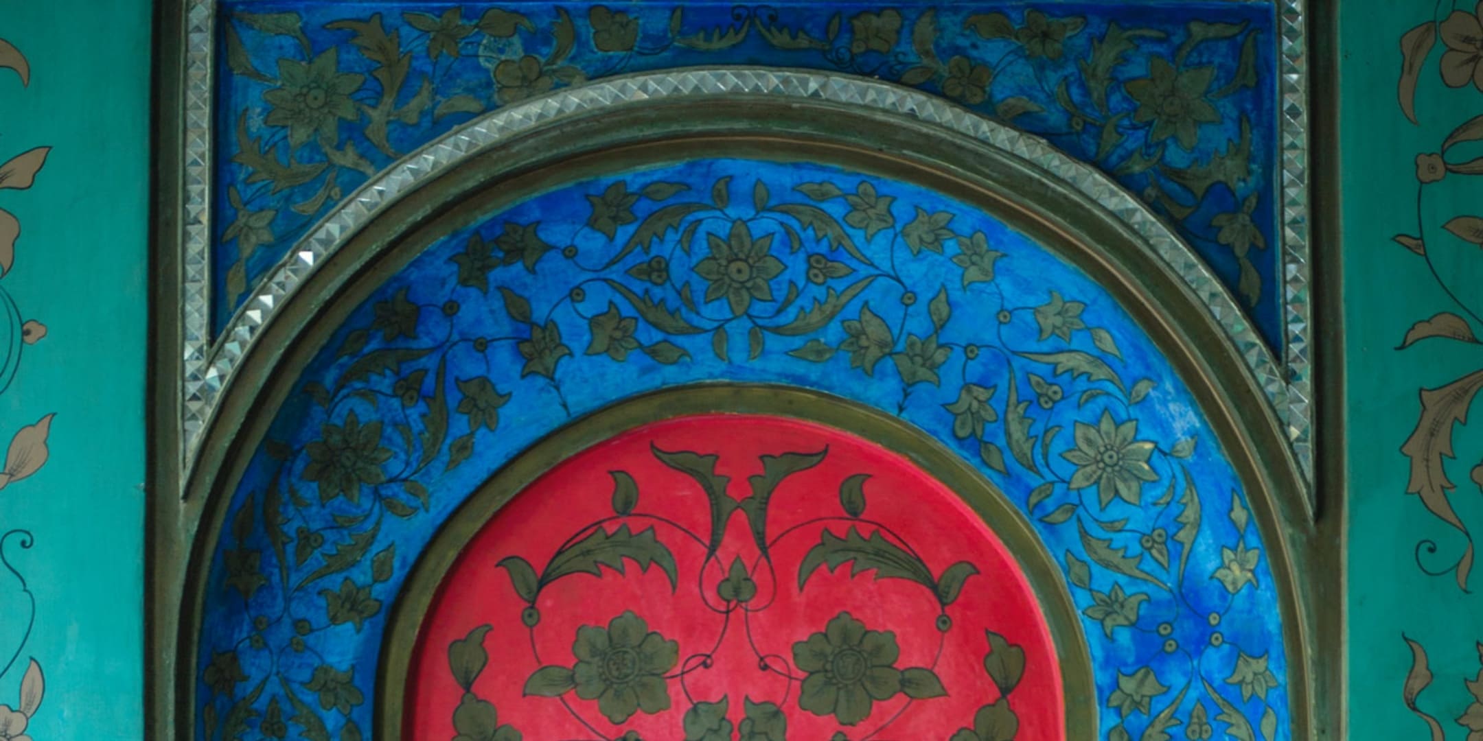 Close-up of an oriental mural with a blue and red arch and detailed floral pattern, inspired by oriental design.